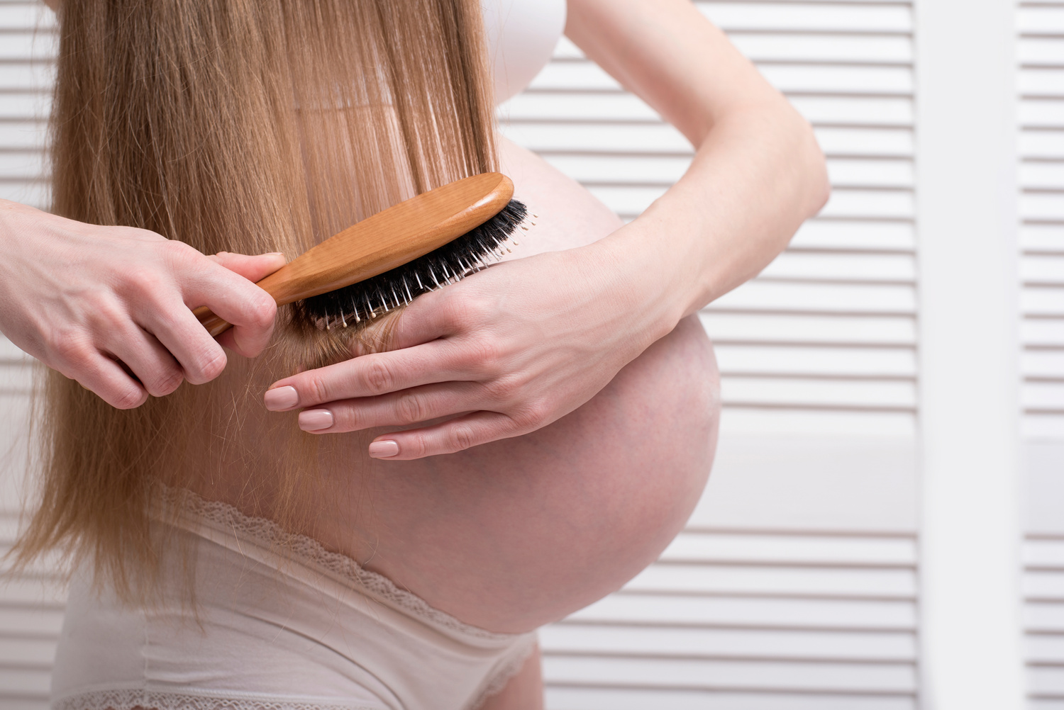 Pregnant Woman Combing Her Long Hair. Close-up. Health Concept